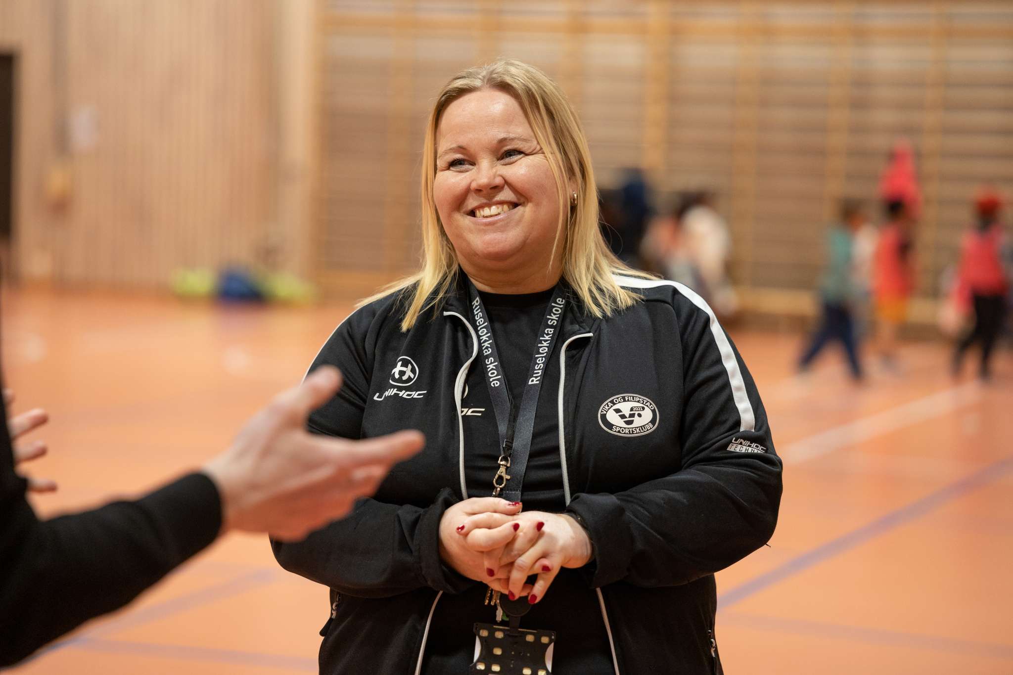 Smilende kvinnelig trener i en gymsal. Foto.