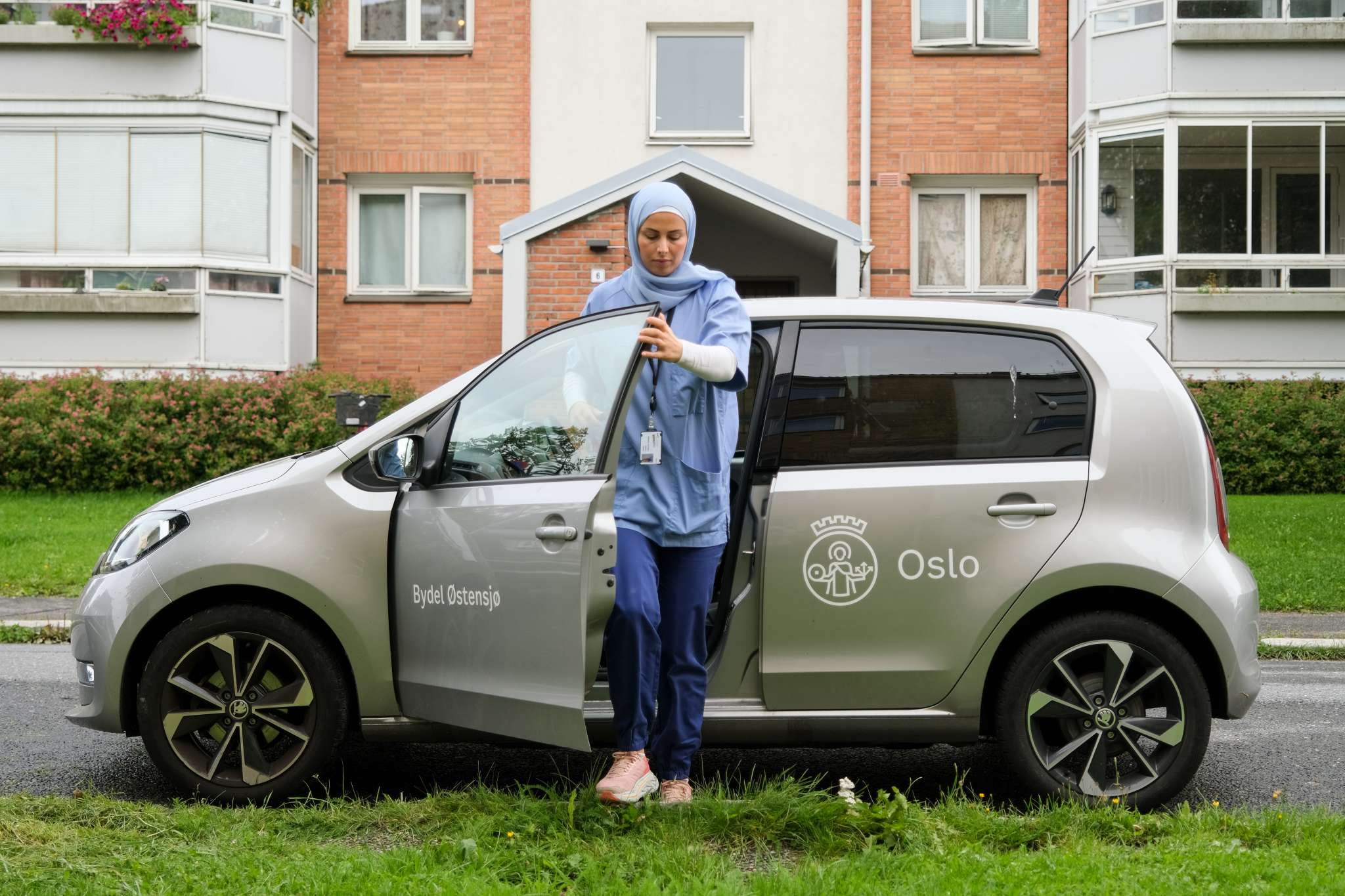 Kvinne på jobb i hjemmesykepleien går ut av bilen sin. Foto.