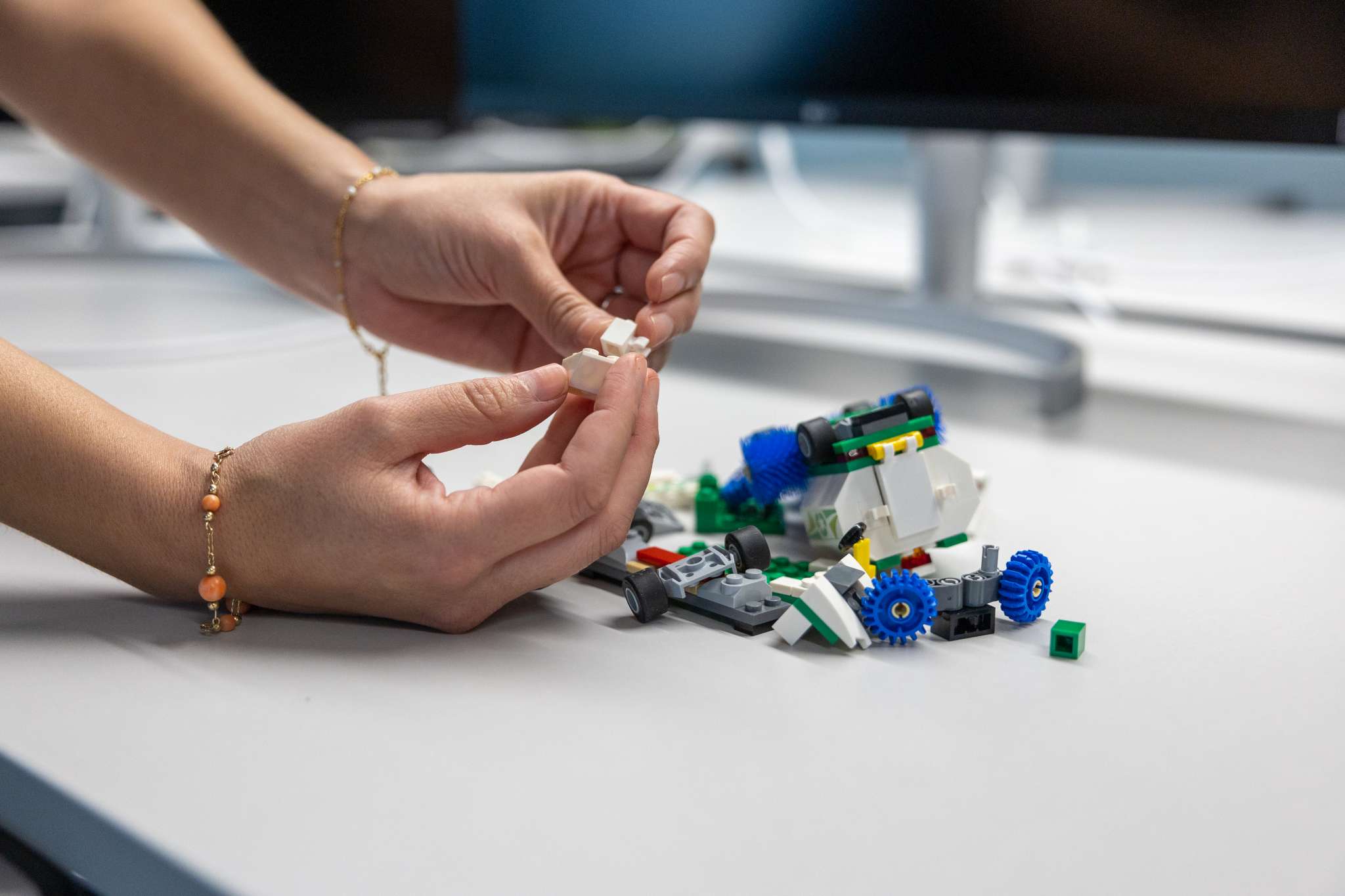 To hender som bygger med legoklosser. Foto.