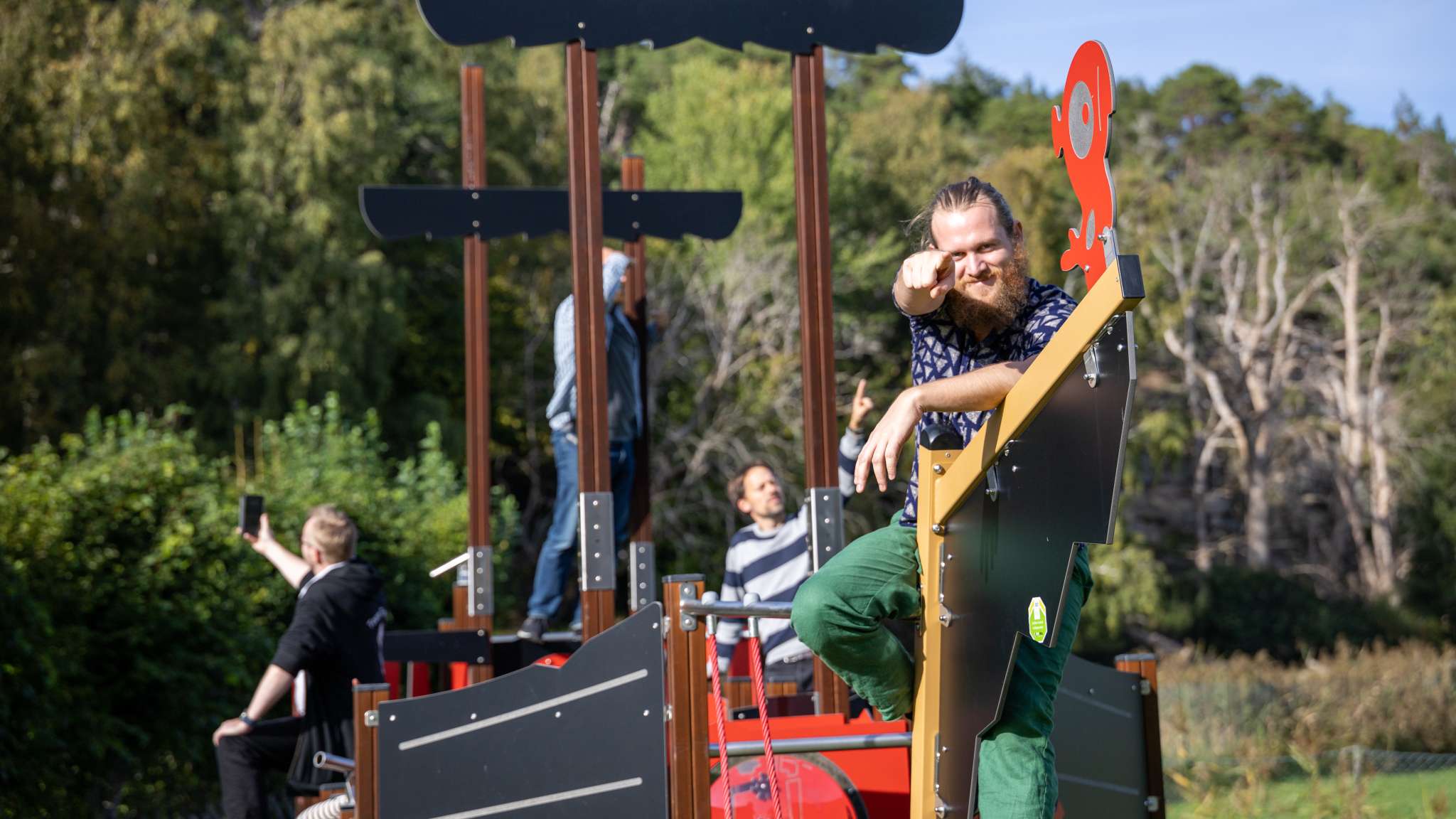 Ansatte i Origo er på en lekeplass, og en person peker rett inn i kamera. Foto.