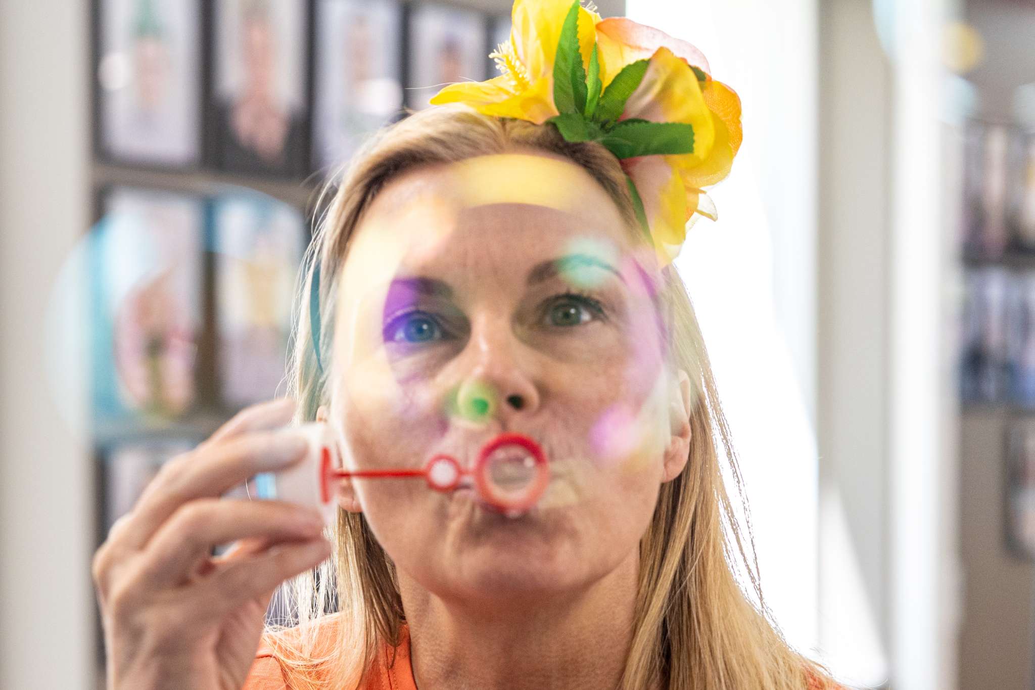 Kvinne er innendørs og blåser såpebobler med blomst i håret.