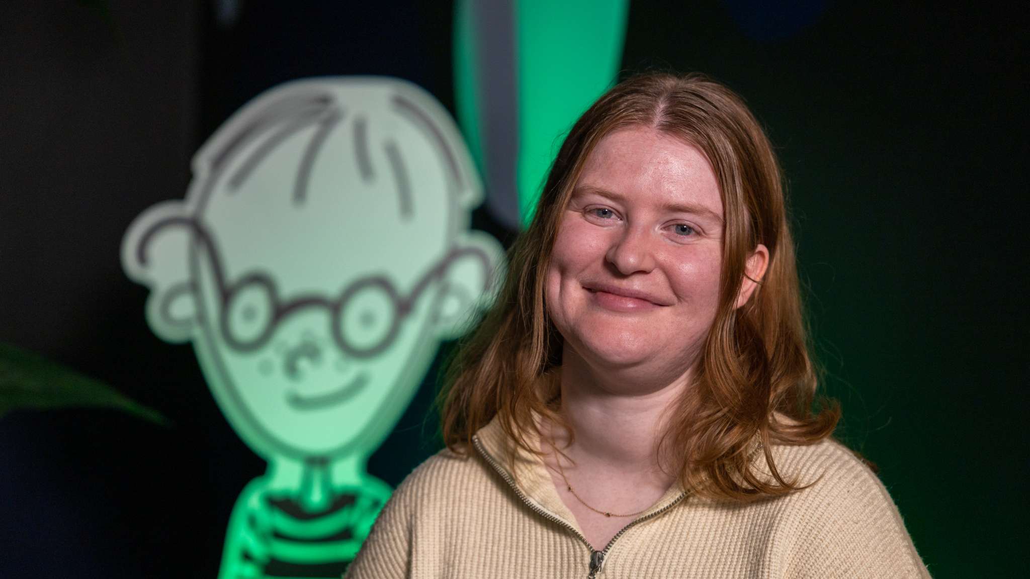 Kvinne står i studioet til Oslo Origo med en Tim-figur i bakgrunnen. Foto.