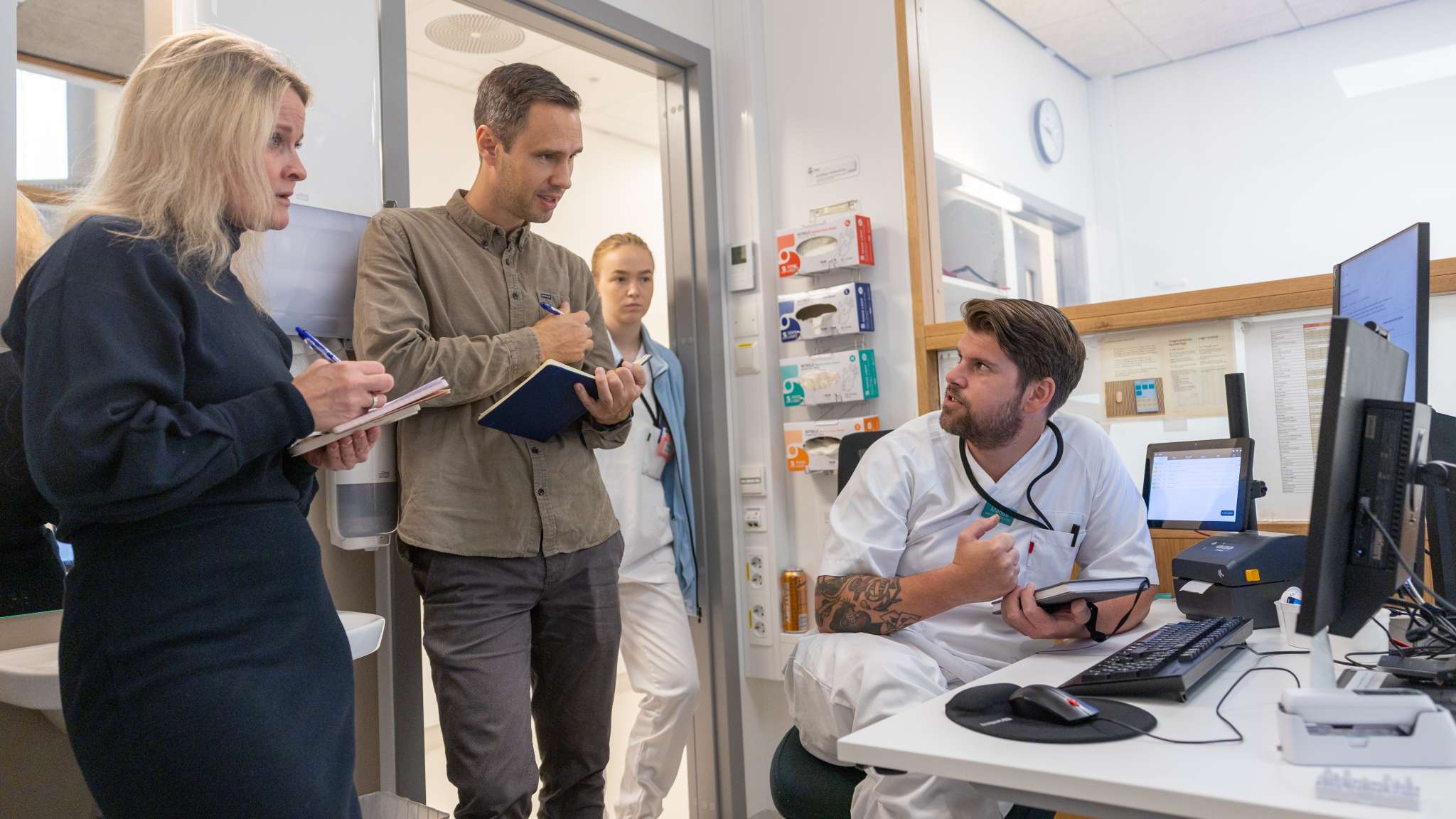 Fire personer snakker sammen på legevakten i Oslo. Foto.