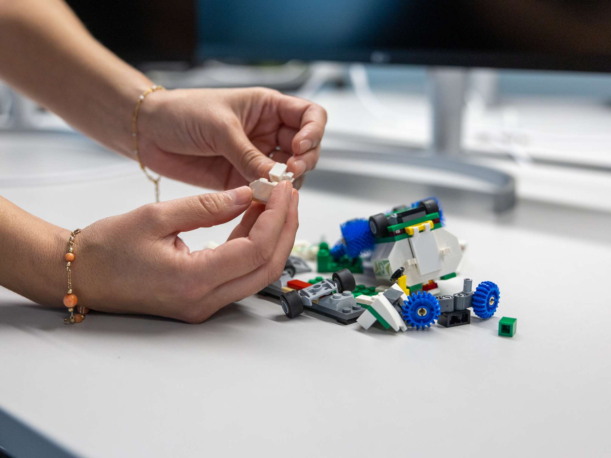 To hender som bygger med legoklosser. Foto.