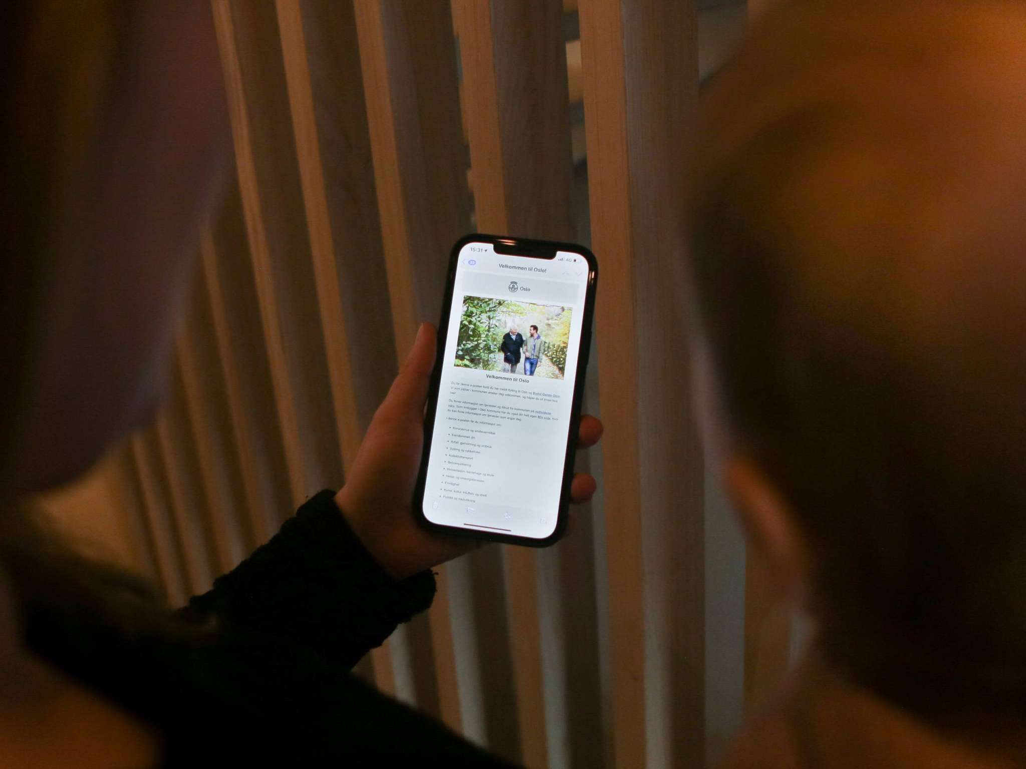 To personer sett bakfra ser på mobil med Velkommen til Oslo-melding