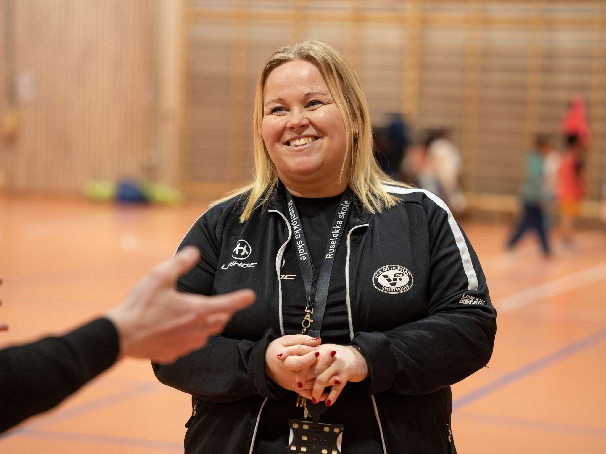 Smilende kvinnelig trener i en gymsal. Foto.
