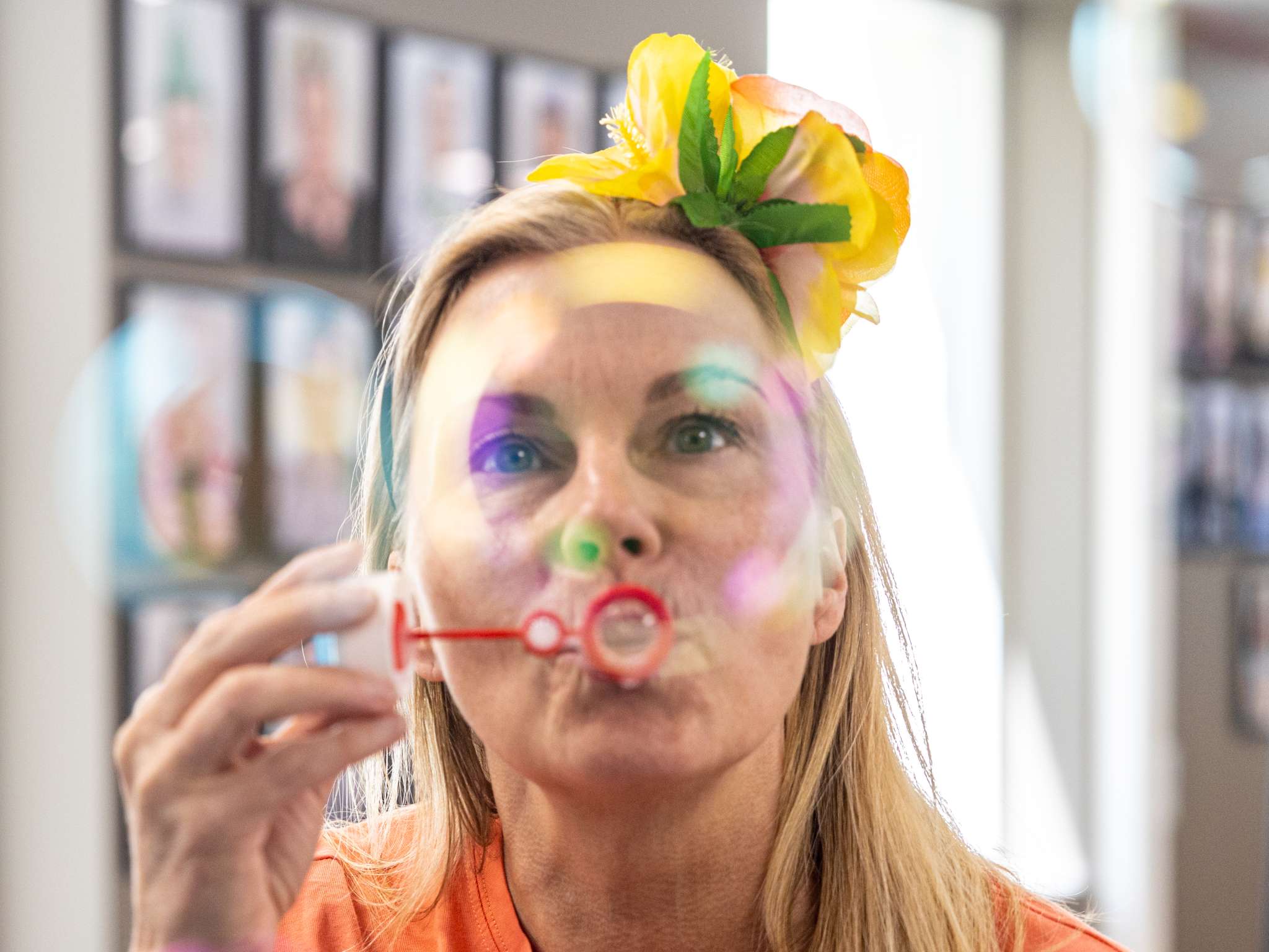 Kvinne er innendørs og blåser såpebobler med blomst i håret.