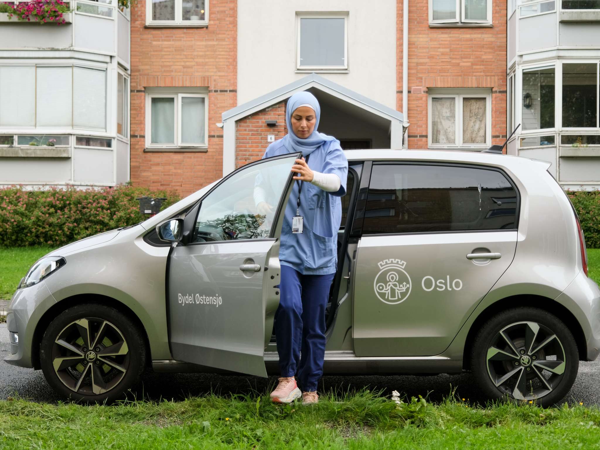 Kvinne på jobb i hjemmesykepleien går ut av bilen sin. Foto.