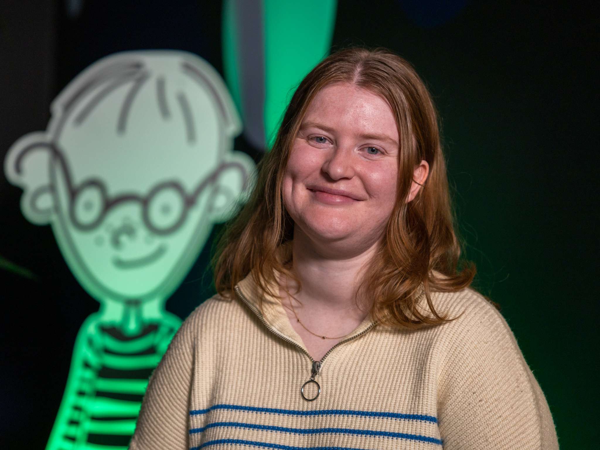 Kvinne står i studioet til Oslo Origo med en Tim-figur i bakgrunnen. Foto.