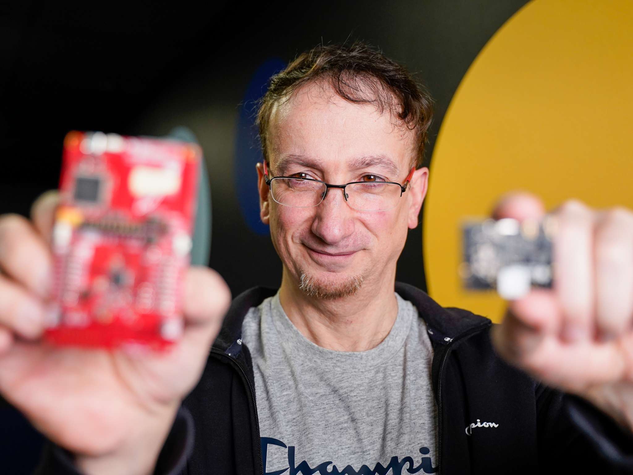 Hardwareutvikler Fred Grønnerød holder en trådløs sender i hver hånd. Foto.