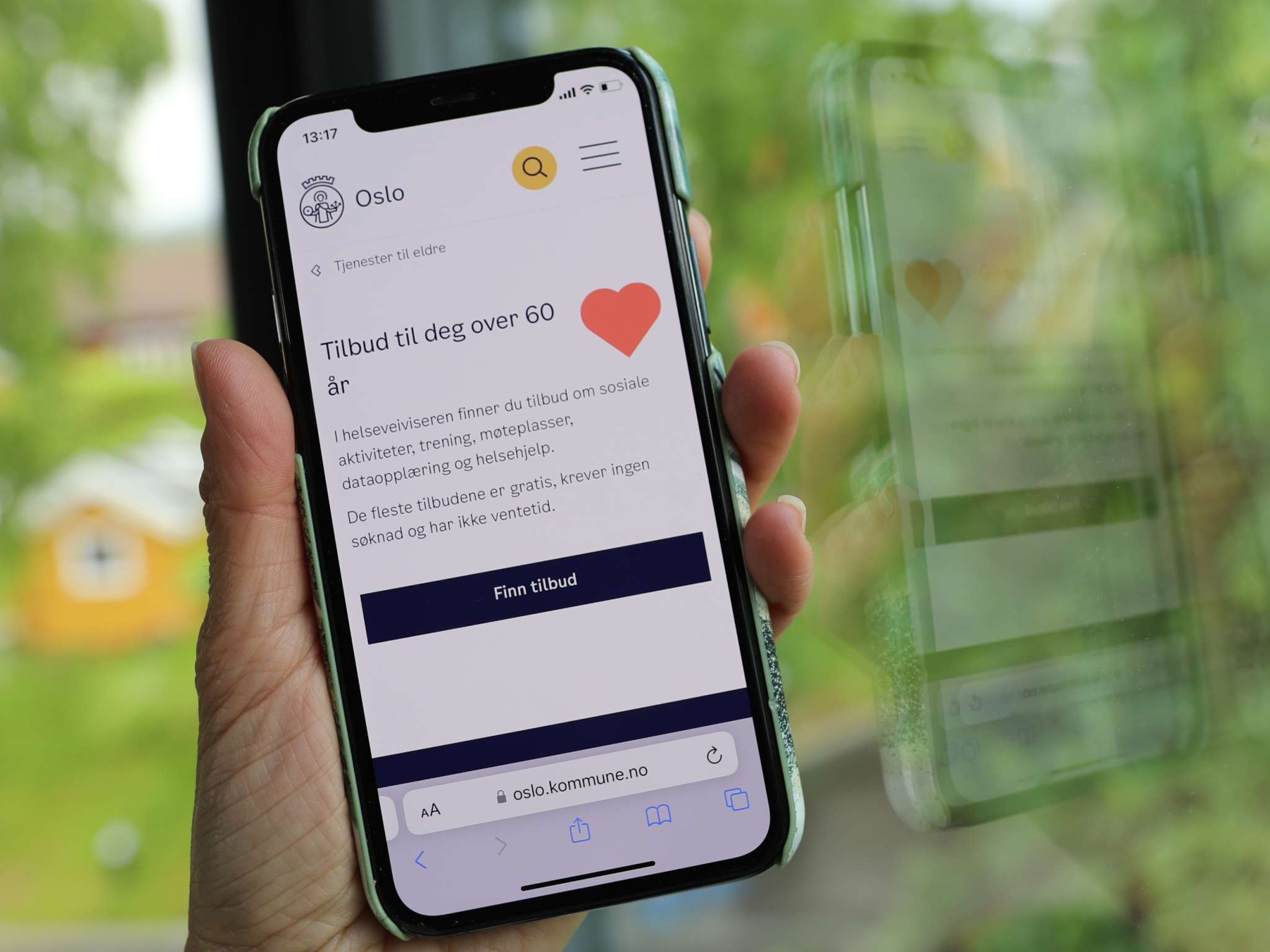 Hånd holder mobil med Helseveiviseren på skjermen