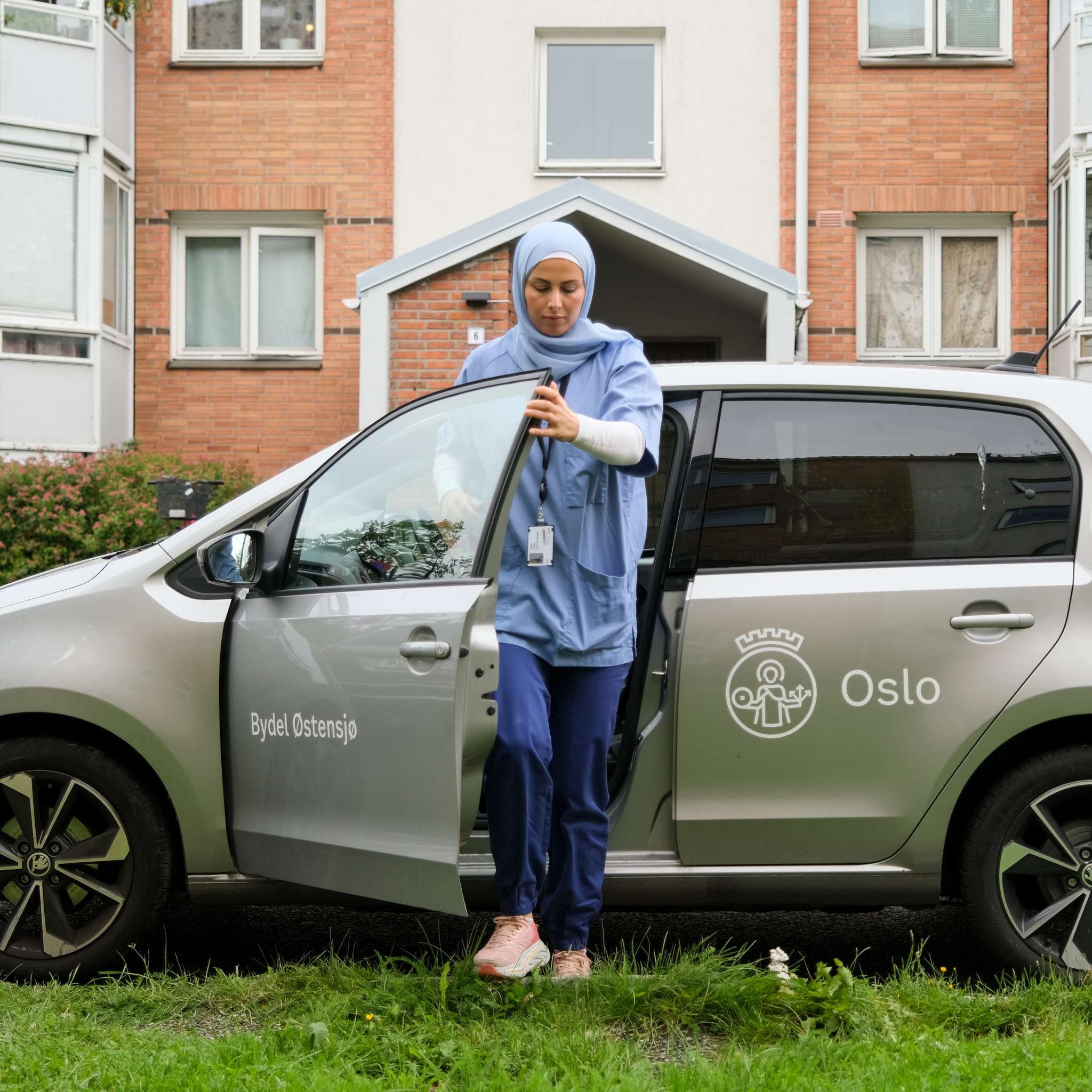 Kvinne på jobb i hjemmesykepleien går ut av bilen sin. Foto.