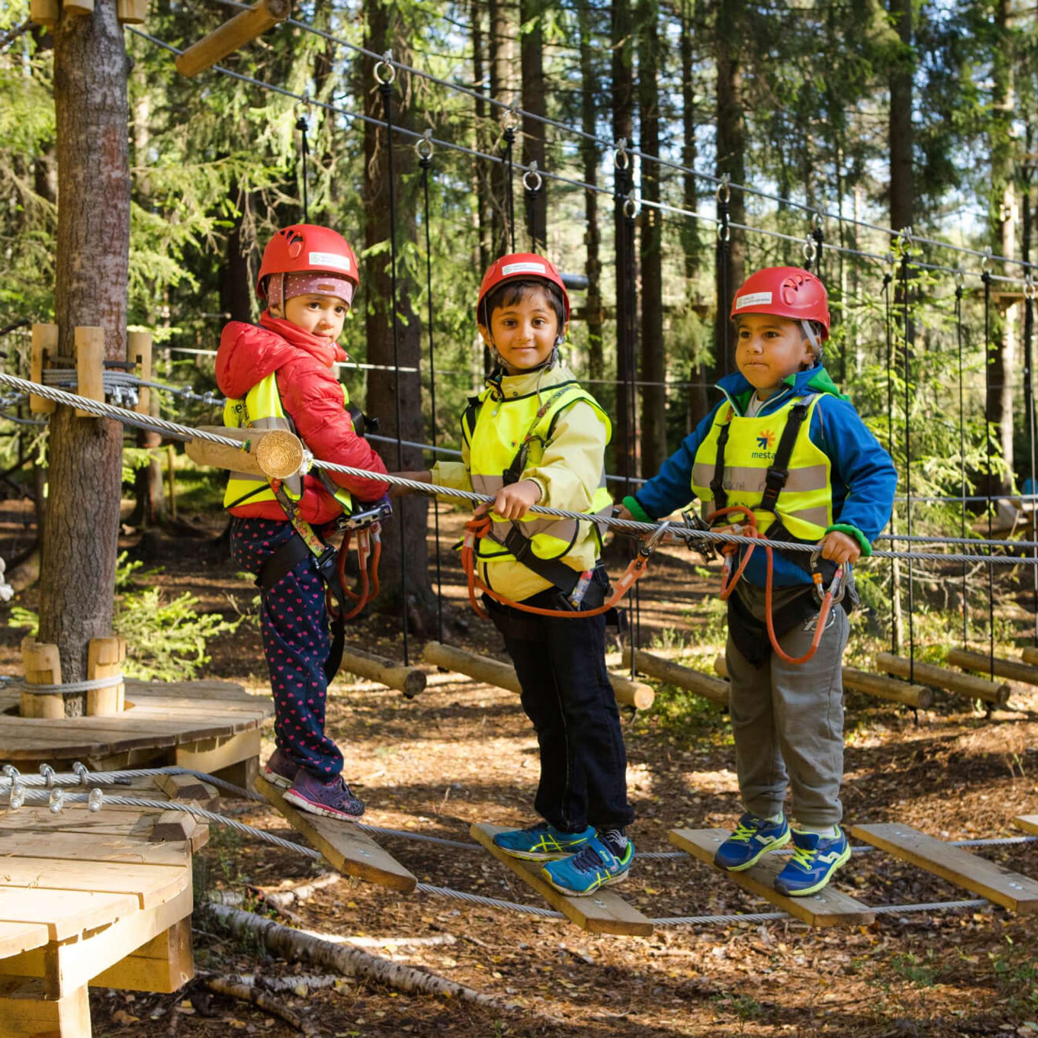 Barnehagebarn leker på taubro i klatrepark. Foto