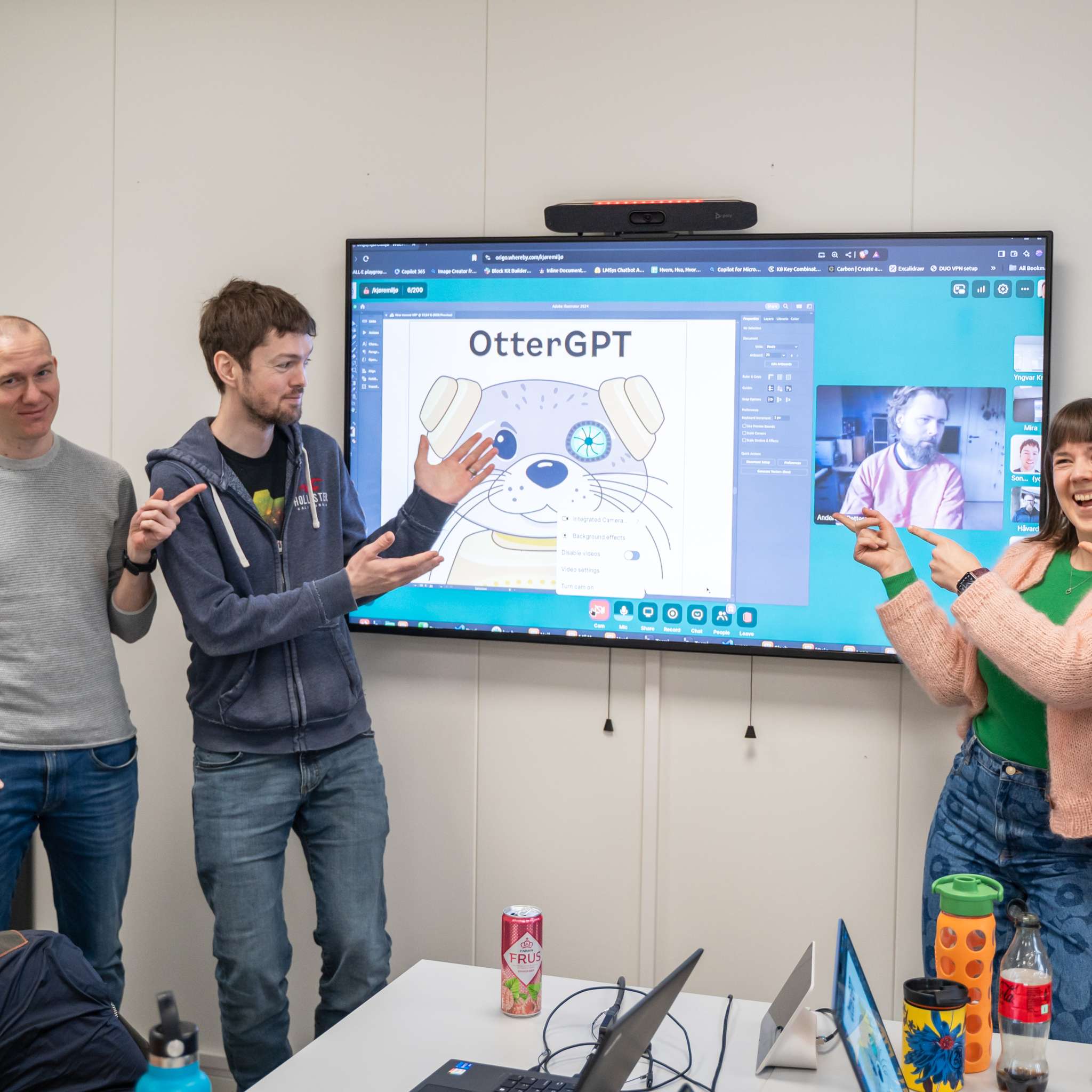 En gjeng med ansatte i Origo står foran en skjerm og viser fram OtterGPT, en selvlaget AI-assistent. Foto.