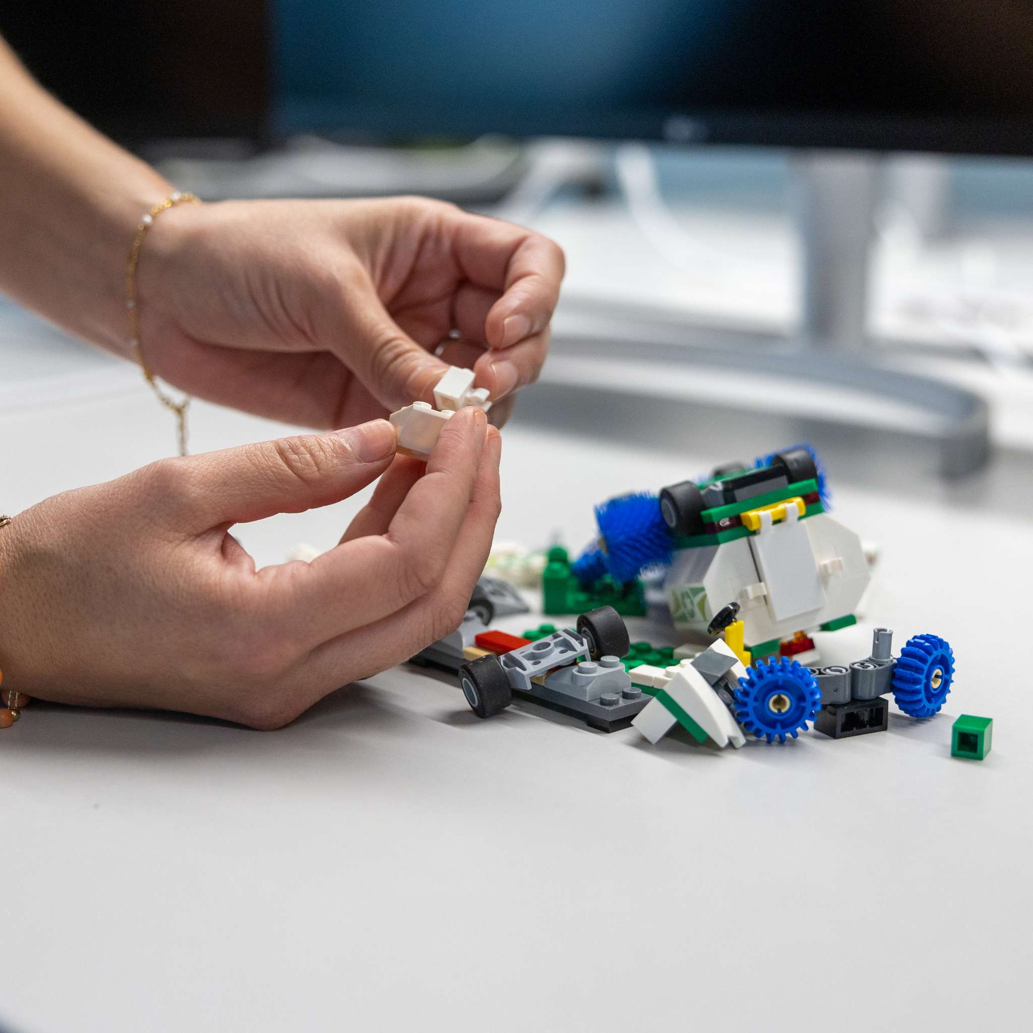 To hender som bygger med legoklosser. Foto.