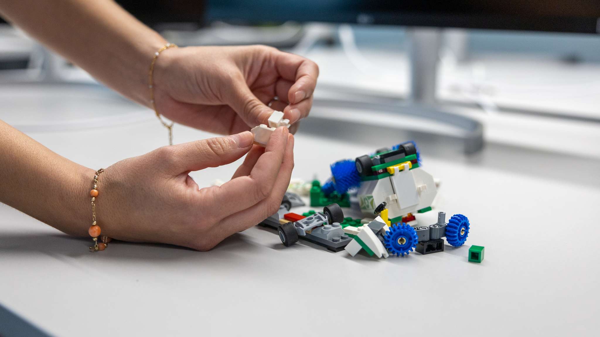 To hender som bygger med legoklosser. Foto.