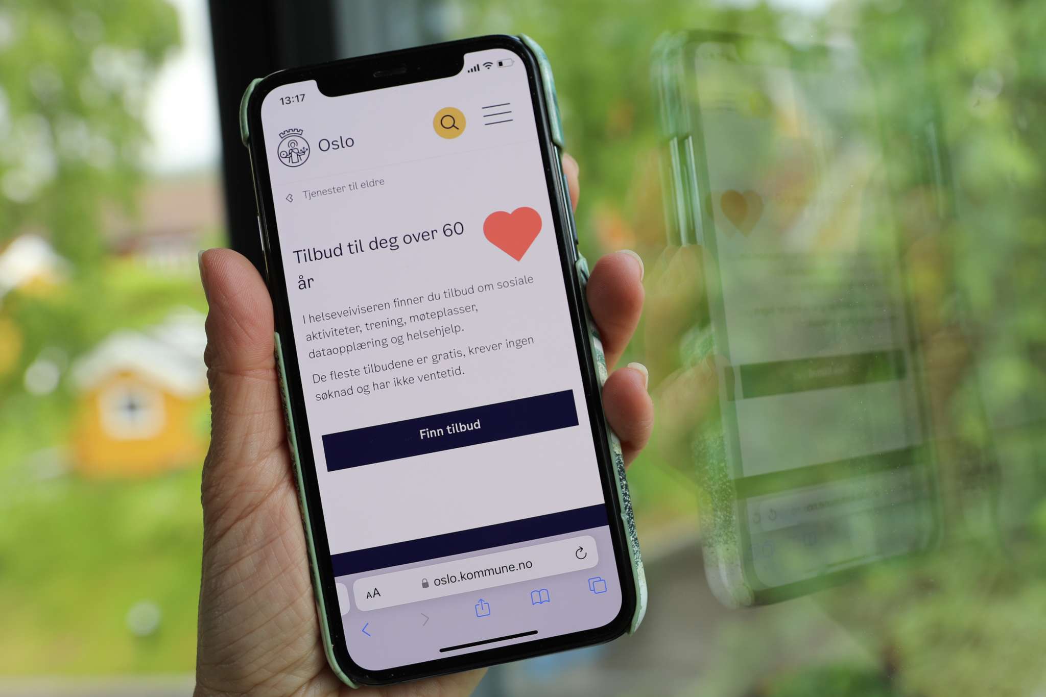 Hånd holder mobil med Helseveiviseren på skjermen