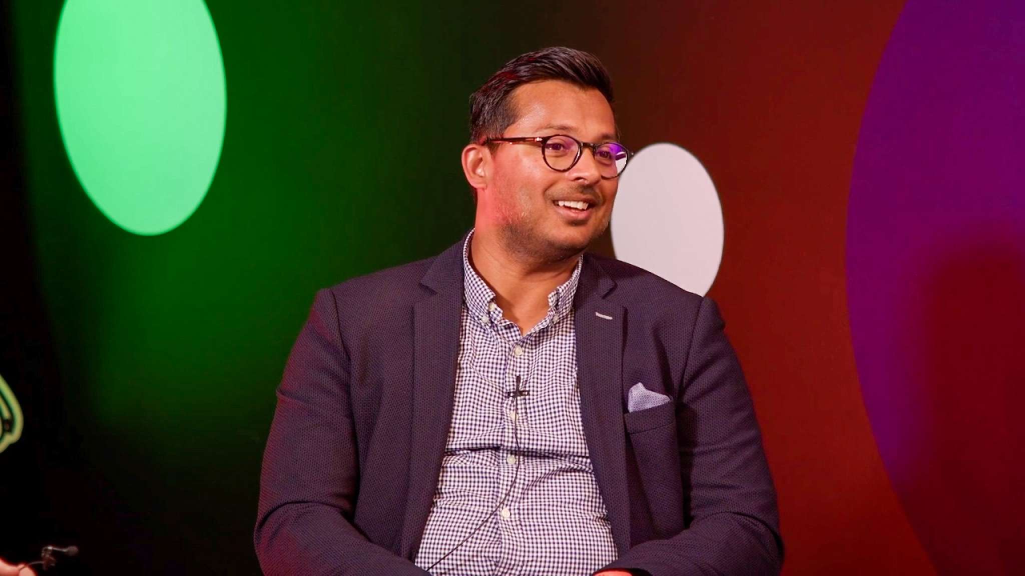 Smilende mann i dress er i studio hos Origo. Foto.