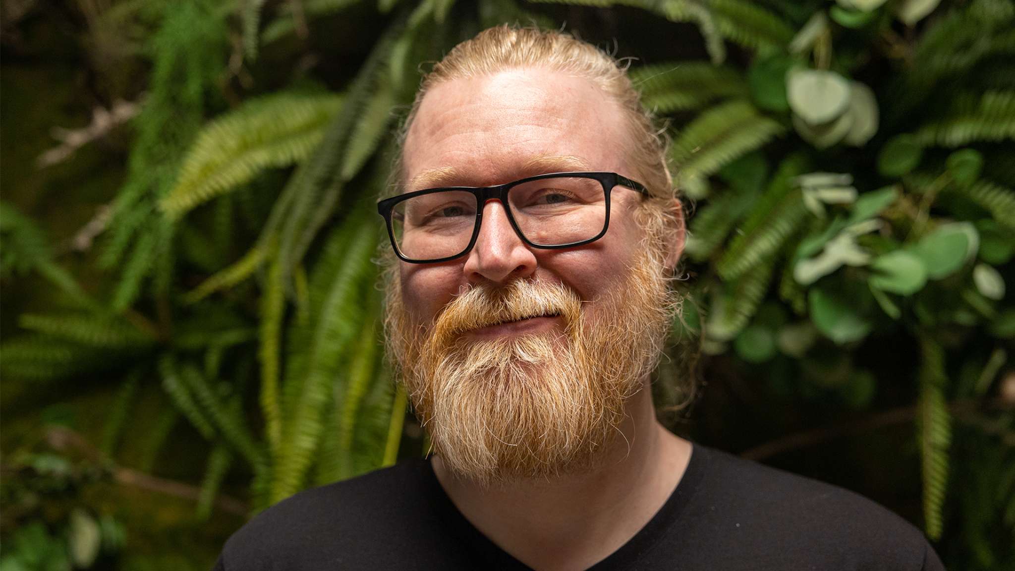 Smilende mann står foran grønn bakgrunn. Bilde.